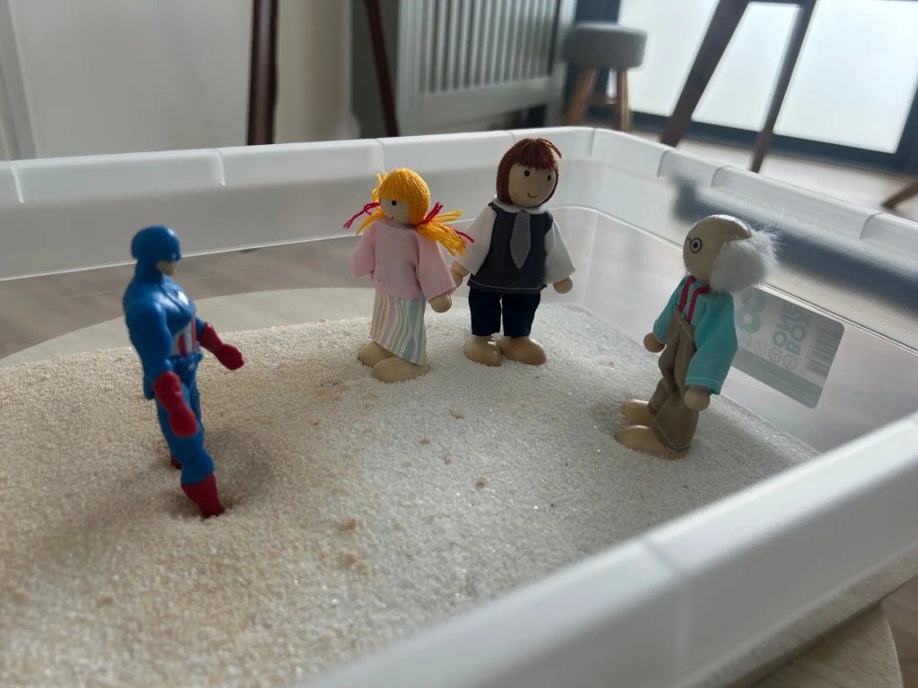 Bac de constellation familiale en séance individuelle à Rennes avec figurines représentant les membres d’une famille.